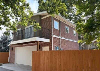 Two-story accessory dwelling unit above a garage with brick exterior and black balcony railing