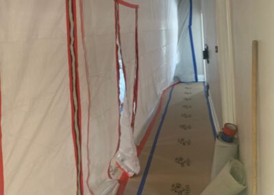Hallway sealed with plastic sheeting and floor protection paper during construction