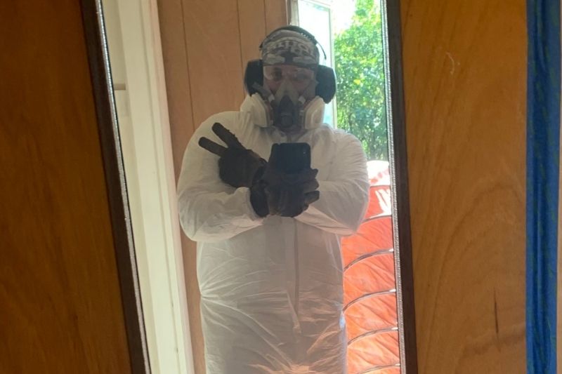 Shane Marberry wearing plastic paint cover, mask, safety goggles, and gloves.