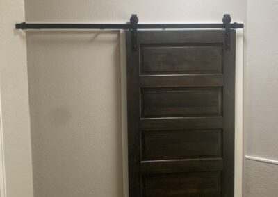 Bathroom nook with a dark wood sliding barn door on black hardware