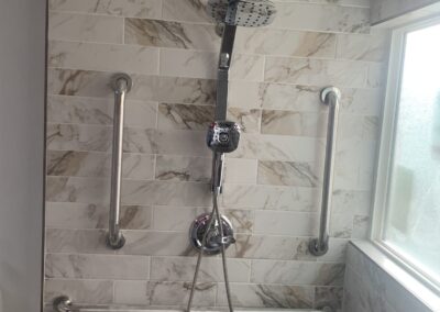 Accessible walk-in shower with marble-look tile, rainfall shower head, and stainless grab bars