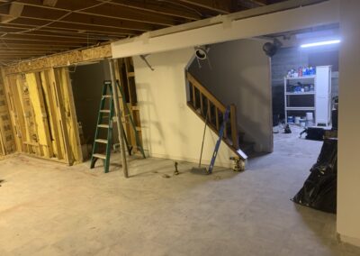 Unfinished basement framing with insulation and ladder before remodel