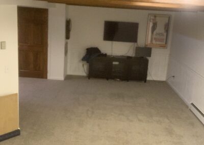 Unfinished basement stairway with wood railing and worn carpet before remodel