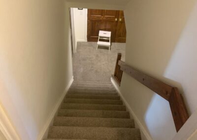 Dated basement rec room with wood TV cabinet and worn carpet before remodel