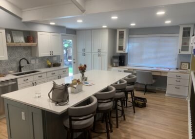 Remodeled kitchen with white cabinets, sage green island, and patterned tile backsplash in Arvada, CO