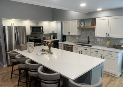 Open kitchen with white shaker cabinets, quartz island, and gray patterned tile backsplash