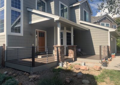 Front porch deck with cable railing, composite decking, and stone columns
