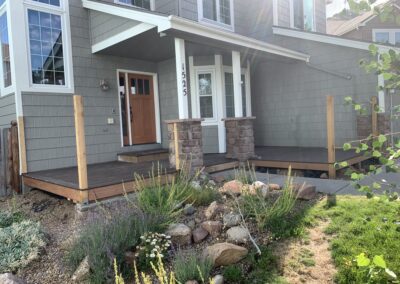 Front porch deck framing with wood posts and stone columns before railing installed