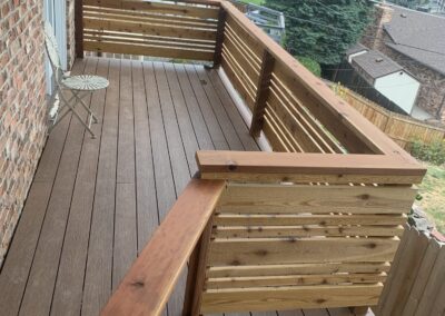 Rooftop balcony deck with cedar slat railing, brick chimney, and neighborhood view