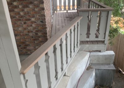 Weathered white porch railing and concrete steps before deck remodel