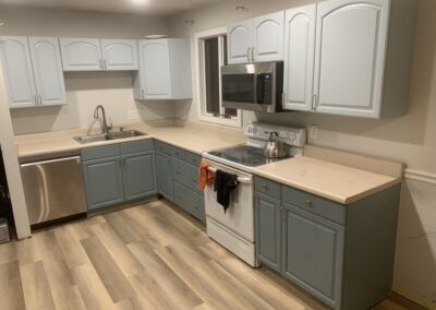Dated kitchen with pale blue cabinets, white electric range, and tile countertops before remodel