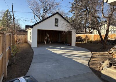 Detached garage with white-painted brick exterior, black roof, and framed interior under construction