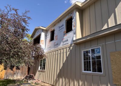 Home addition under construction with house wrap and new window openings