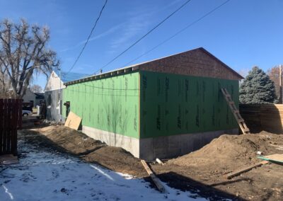 New home addition under construction with green weather-resistant sheathing and concrete foundation