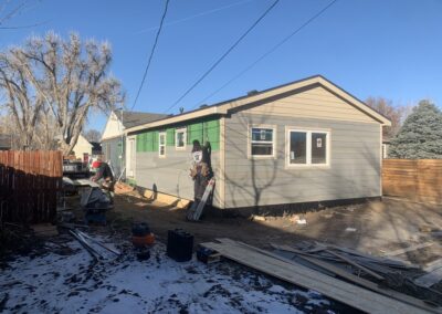Home addition exterior with new two-tone lap siding installed by workers on a ladder