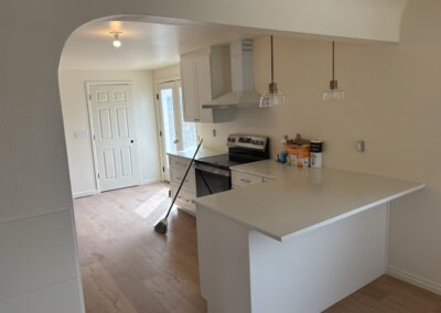 White kitchen with range hood, pendant lighting, and stainless range