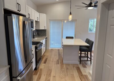 Remodeled kitchen with white cabinets, quartz island, pendant lighting, and hardwood flooring