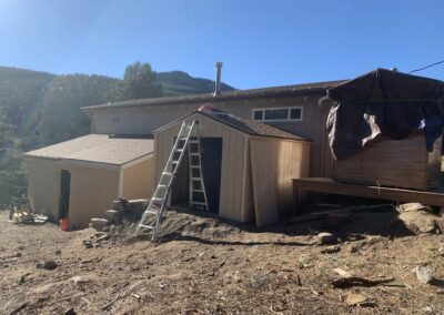 Mountain home addition under construction with a shed roof and tarped materials