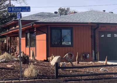 Ranch house exterior with orange board-and-batten siding and black trim after remodel